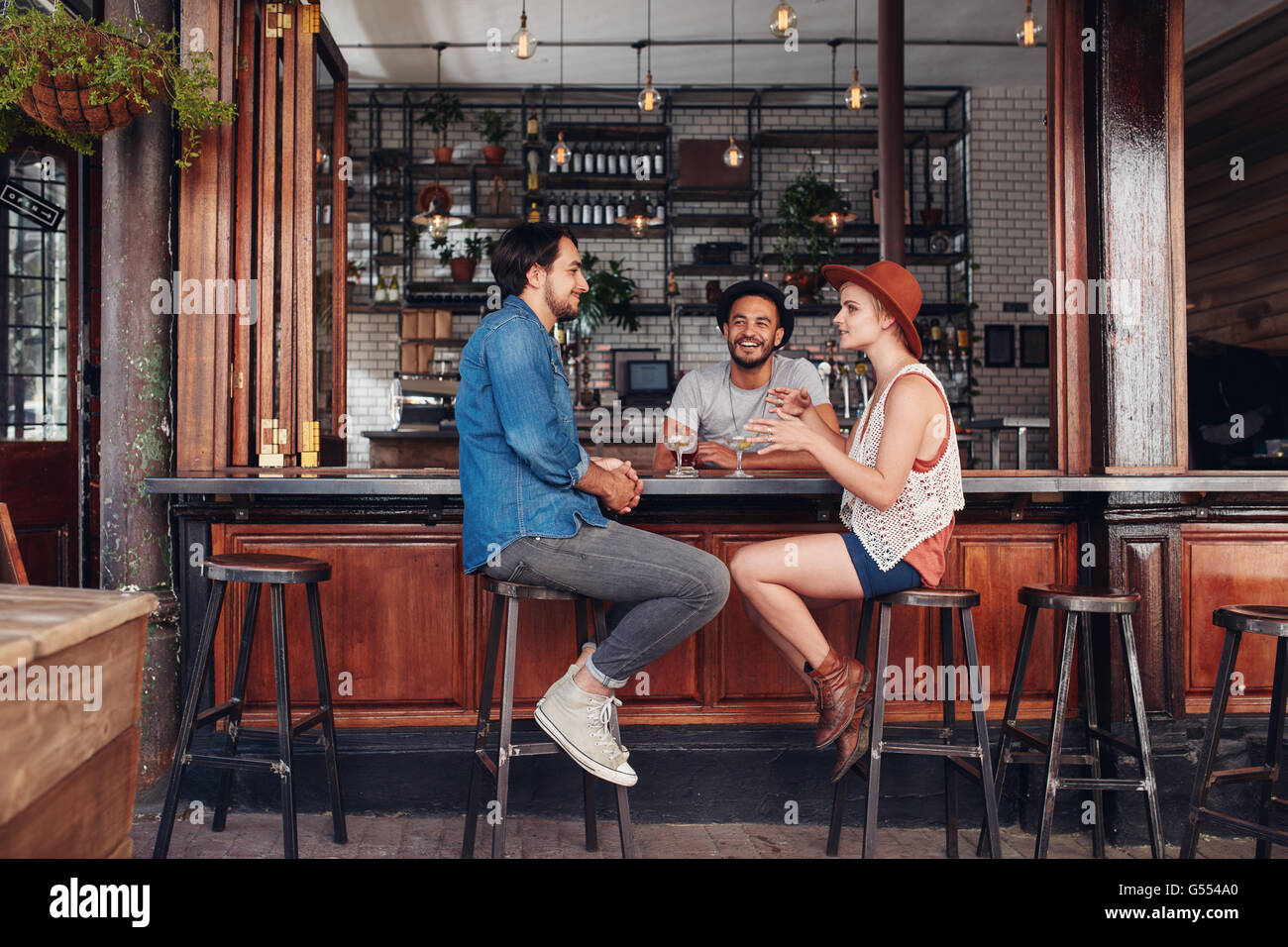 Porträt von glücklichen Gruppe von Jugendlichen in einem Café zu treffen und reden. Drei junge Freunde an einem Cafétisch sitzen. Stockfoto