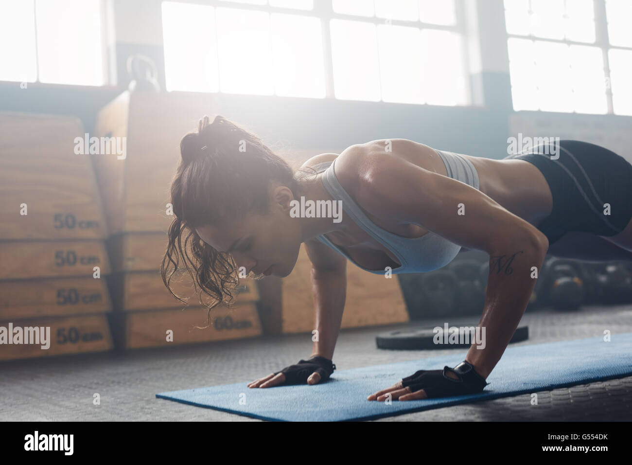 Aufnahme der jungen Frau, die Liegestütze in der Turnhalle zu tun. Muskuläre weiblich Liegestütze auf Trainingsmatte im Fitnessstudio zu tun. Weiblich, die Ausübung auf fitnes Stockfoto