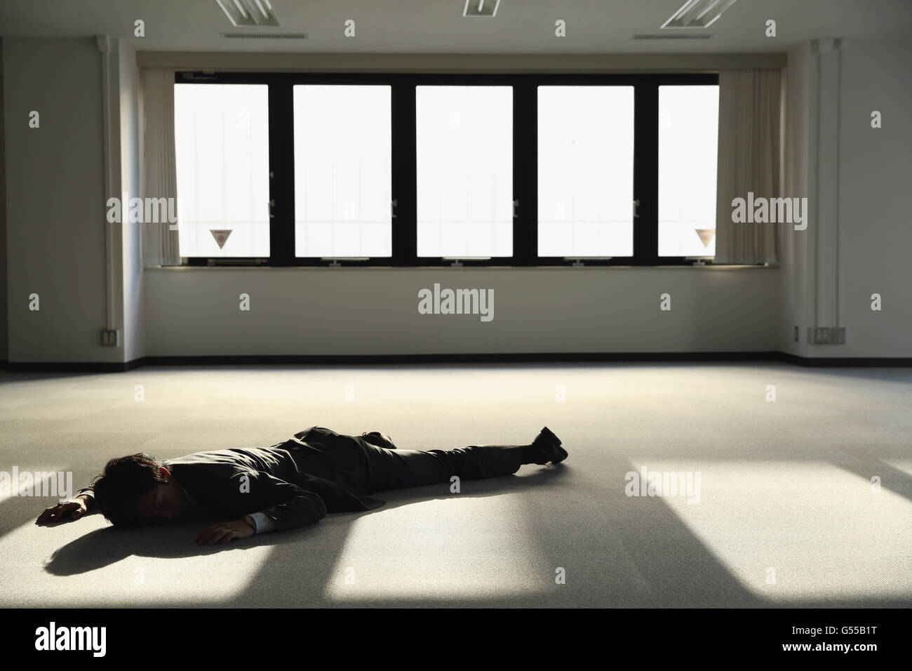Junge japanische Geschäftsmann tot auf dem Boden ein leeres Büro Stockfoto