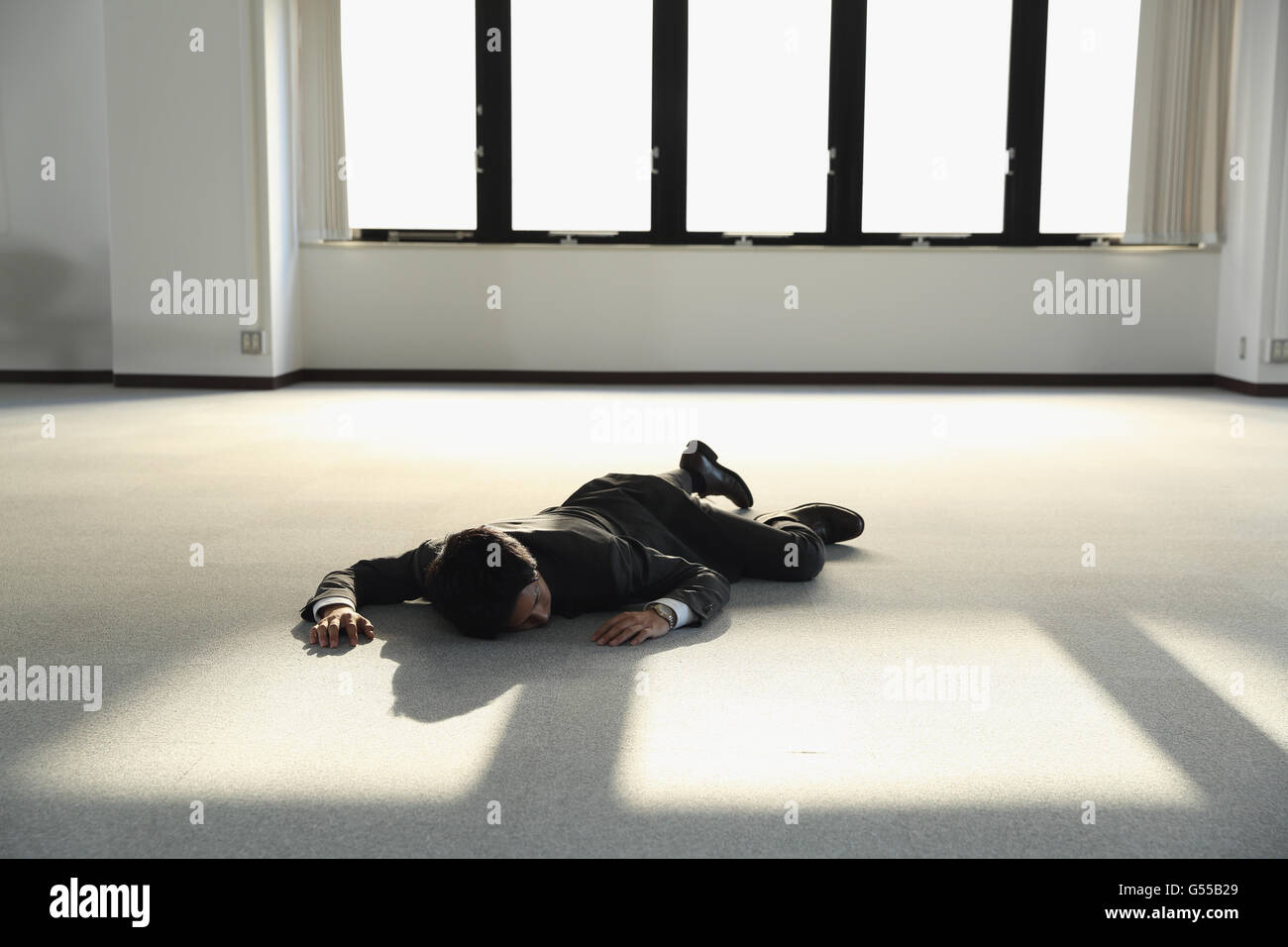 Junge japanische Geschäftsmann tot auf dem Boden ein leeres Büro Stockfoto