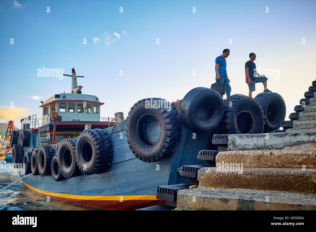 Am Ende ihres Arbeitstages steigen Arbeiter einer Dschunke in der neuen Yau Ma Tei Typhoon Shelter in Kowloon, Hongkong. Stockfoto