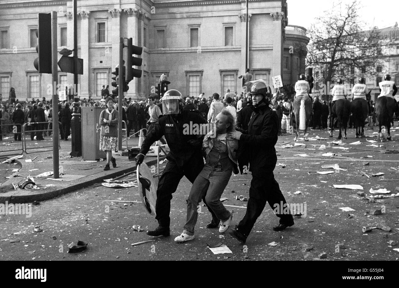 Polizeibeamte in Bereitschaftskleidung verhaften einen Protestierenden in der Nähe der National Gallery, Trafalgar Square, London, nachdem sich eine Demonstration gegen die Abgabensteuer zu einem Aufruhr entwickelt hatte. Berittene Offiziere können im Hintergrund gesehen werden, Blick auf Charing Cross Rd. Stockfoto