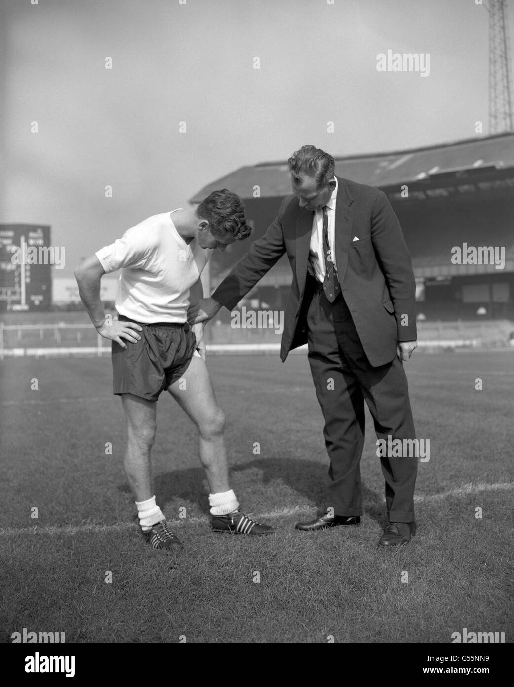Der englische Teamchef Walter Winterbottom (r) spricht mit dem englischen Kapitän Johnny Haynes auf der Stamford Bridge über das verletzte Bein, das Letzteres aus dem WM-Spiel gegen Luxemburg heraushalten wird. Haynes zog einen Muskel in seinem linken Oberschenkel während Fulhams Spiel mit Ipswich Town. Stockfoto