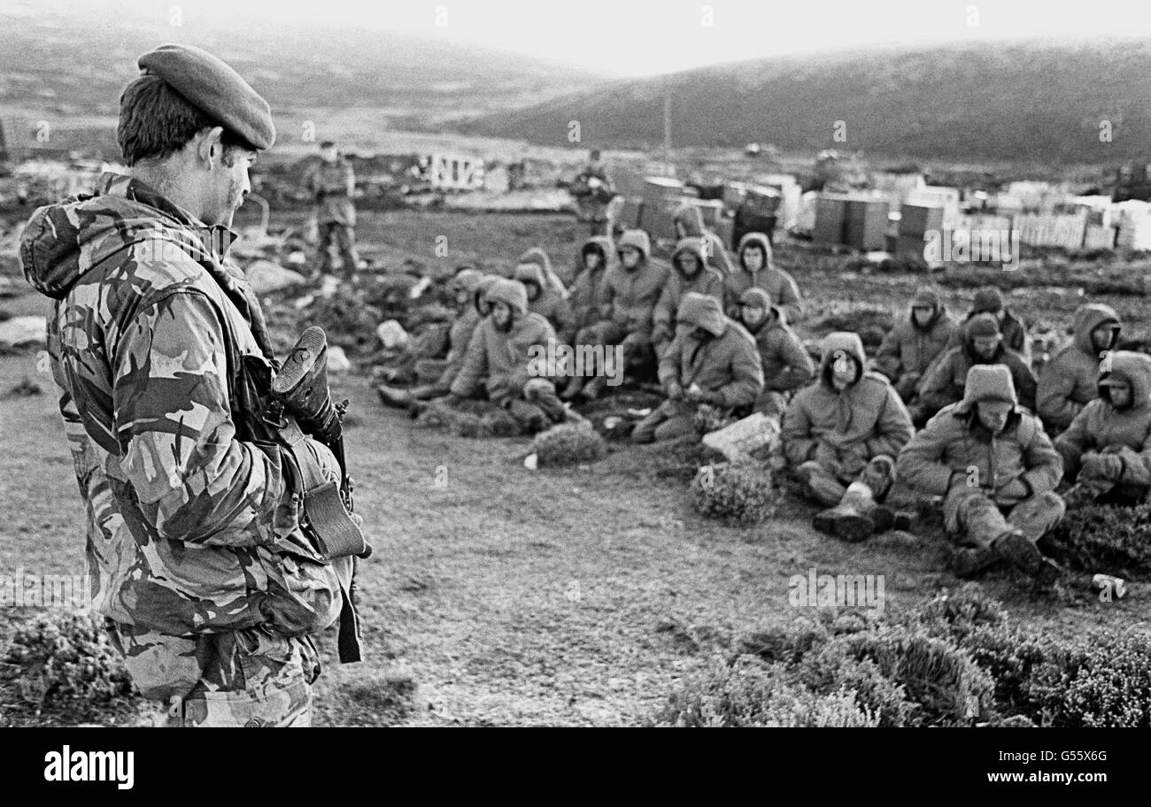 DER FALKLANDKRIEG 1982: Argentinische Soldaten, die bei Goose Green gefangen genommen wurden, werden von einer britischen Royal Marine bewacht, während sie auf den Transit aus dem Gebiet warten. Goose Green wurde von Männern des Fallschirmregiments, Teil der britischen Task Force, gefangen genommen. 825/03/02 Argentinische Soldaten gefangen bei Goose Green wird von einem britischen Royal Marine bewacht, wie sie den Transit aus dem Bereich warten. Der 20. Jahrestag der Invasion der Falklandinseln durch argentinische Truppen wird am 2. April 2002 stattfinden. Stockfoto