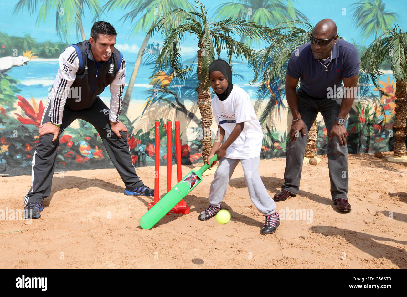 Sadiya Ali aus dem 2. Jahr erhält eine Lektion von dem englischen Cricketspieler Kevin Pietersen (links) und dem ehemaligen westindischen Cricketspieler Sir Viv Richards während der Feierlichkeiten zum fünften Jahrestag von Chance to Shine's Brit Insurance National Cricket Day mit karibischem Cricket-Thema an der Johanna Primary School in London. Stockfoto