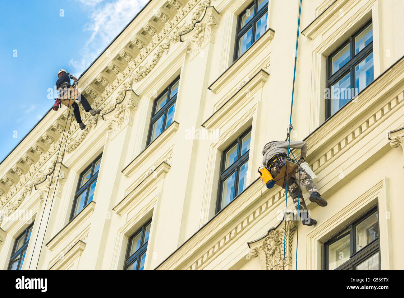 Zwei Männer, die an Seilen aufgehängt malen Sie das äußere eines Mehrfamilienhauses im Zentrum von Budapest, Ungarn. Stockfoto