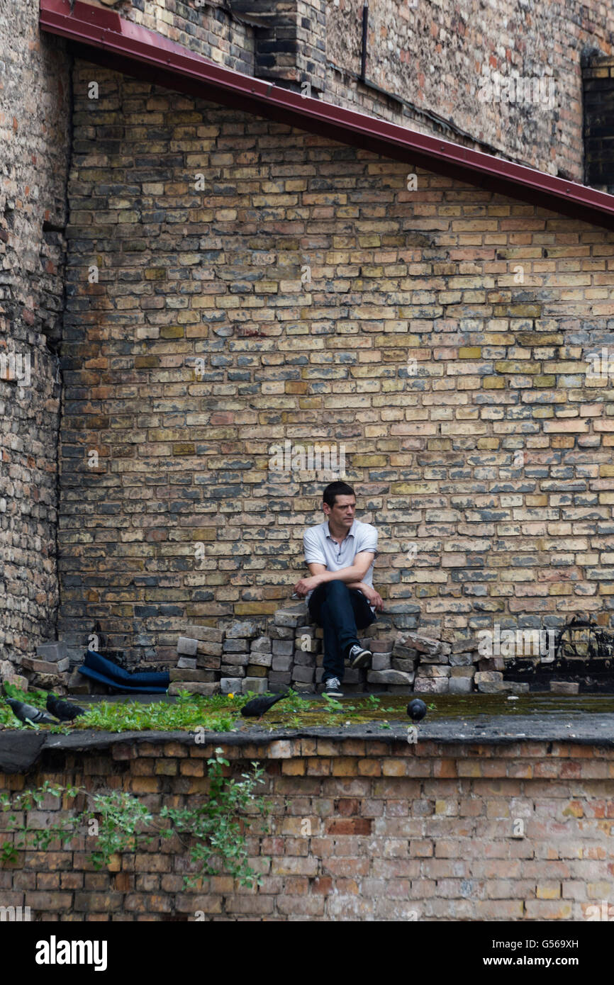 VILNIUS, Litauen - 8. Juni 2016: Ein unbekannter Mann raucht eine Zigarette auf dem Dach eines alten Hauses. Vintage Verarbeitung Stockfoto