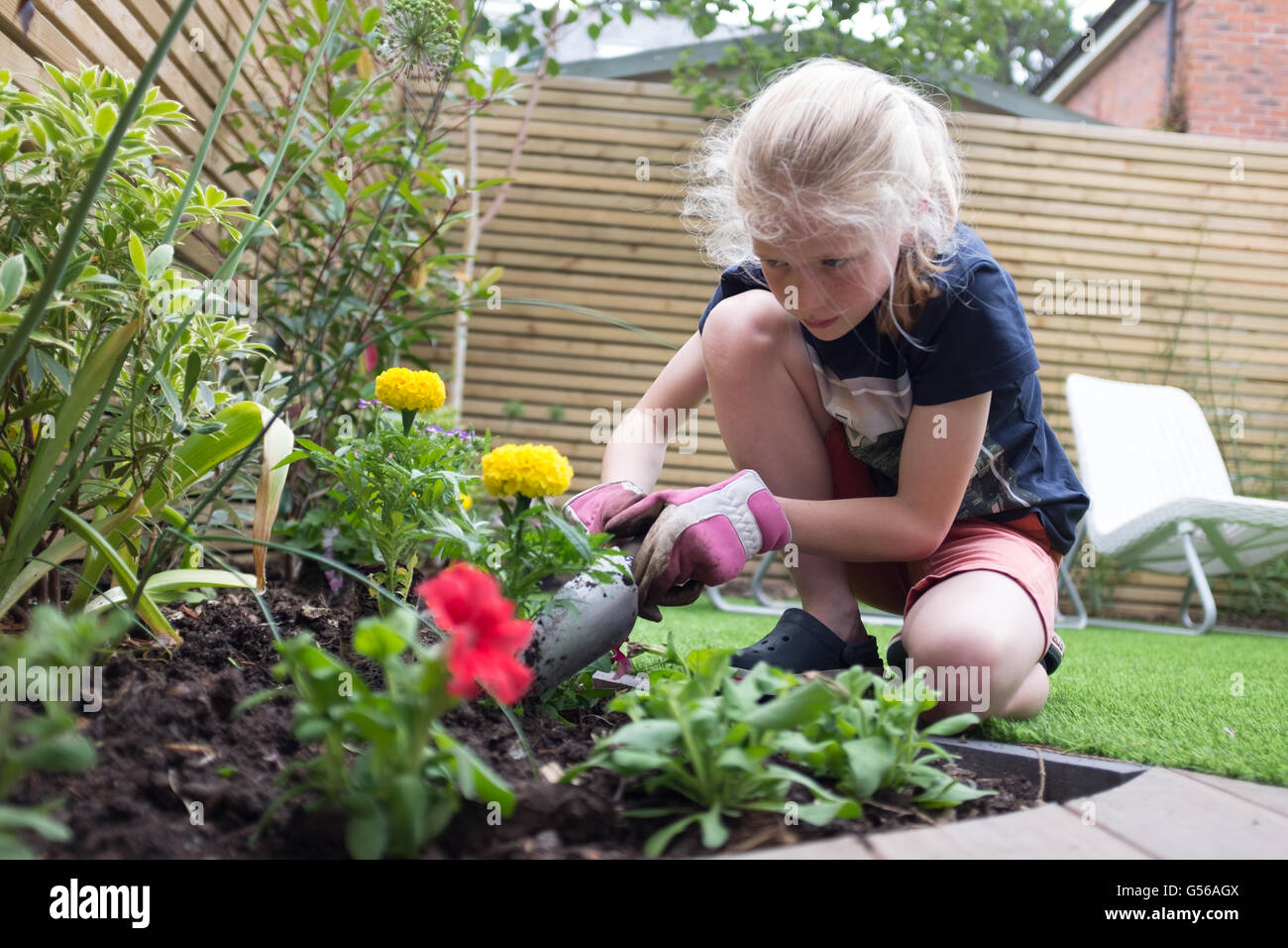 Ein junges Mädchen in einem zeitgenössischen UK Garten Gartenarbeit Stockfoto