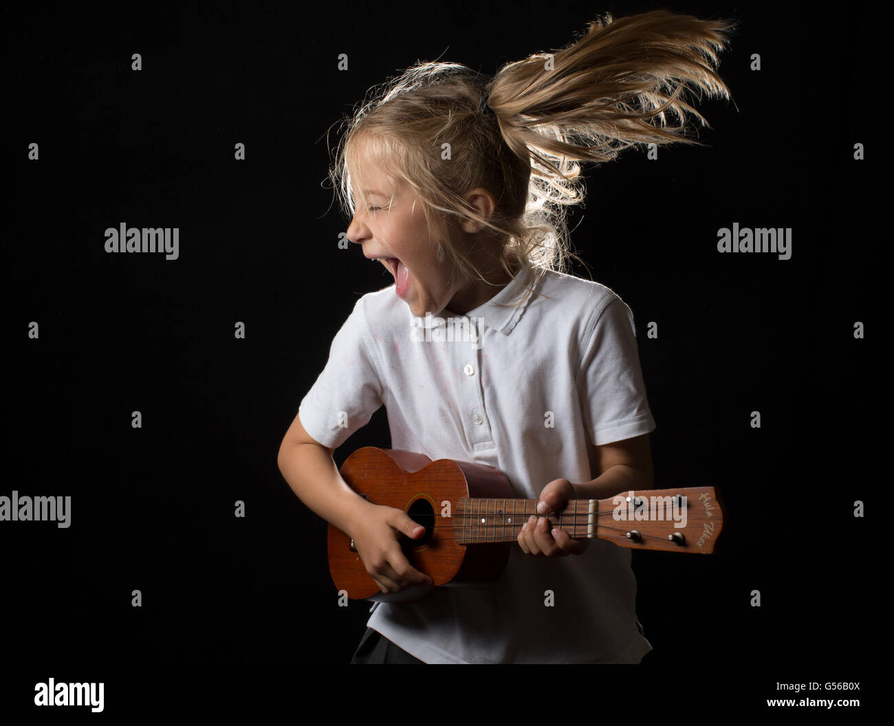 Humorvolle Studio-Porträt eines jungen Mädchens, singen und spielen der Ukulele. Stockfoto