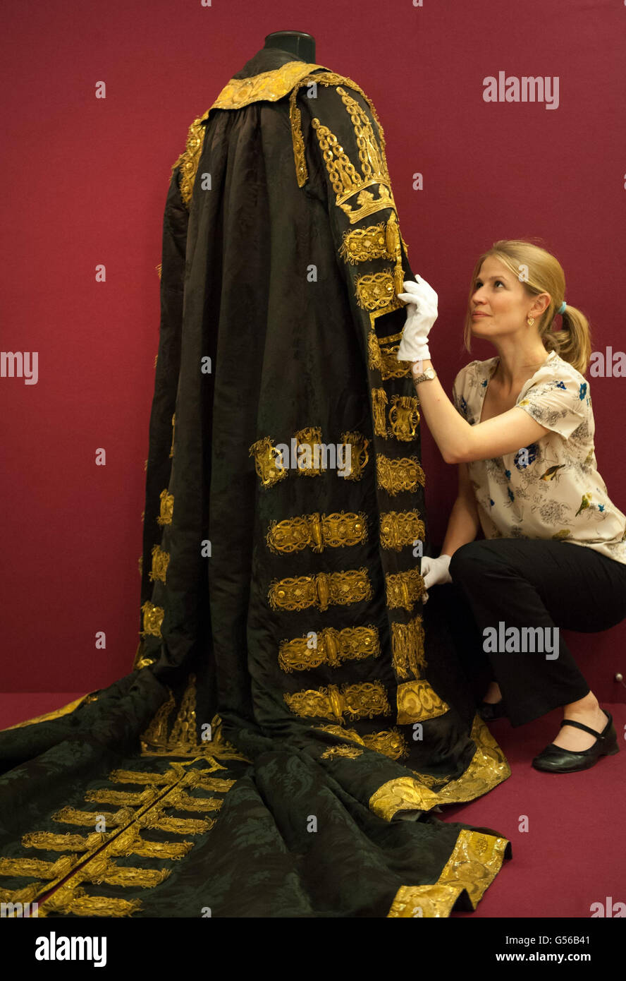 Die Ausstellungsassistentin Nancy Tanner passt die Roben des Lord Chamberlain an, die Teil der Ausstellung „Gold: Power and Allure“ der Goldsmiths Company ist, die vom 1. Juni bis 28 2012. Juli in der Goldsmiths Hall im Zentrum Londons stattfindet. Stockfoto