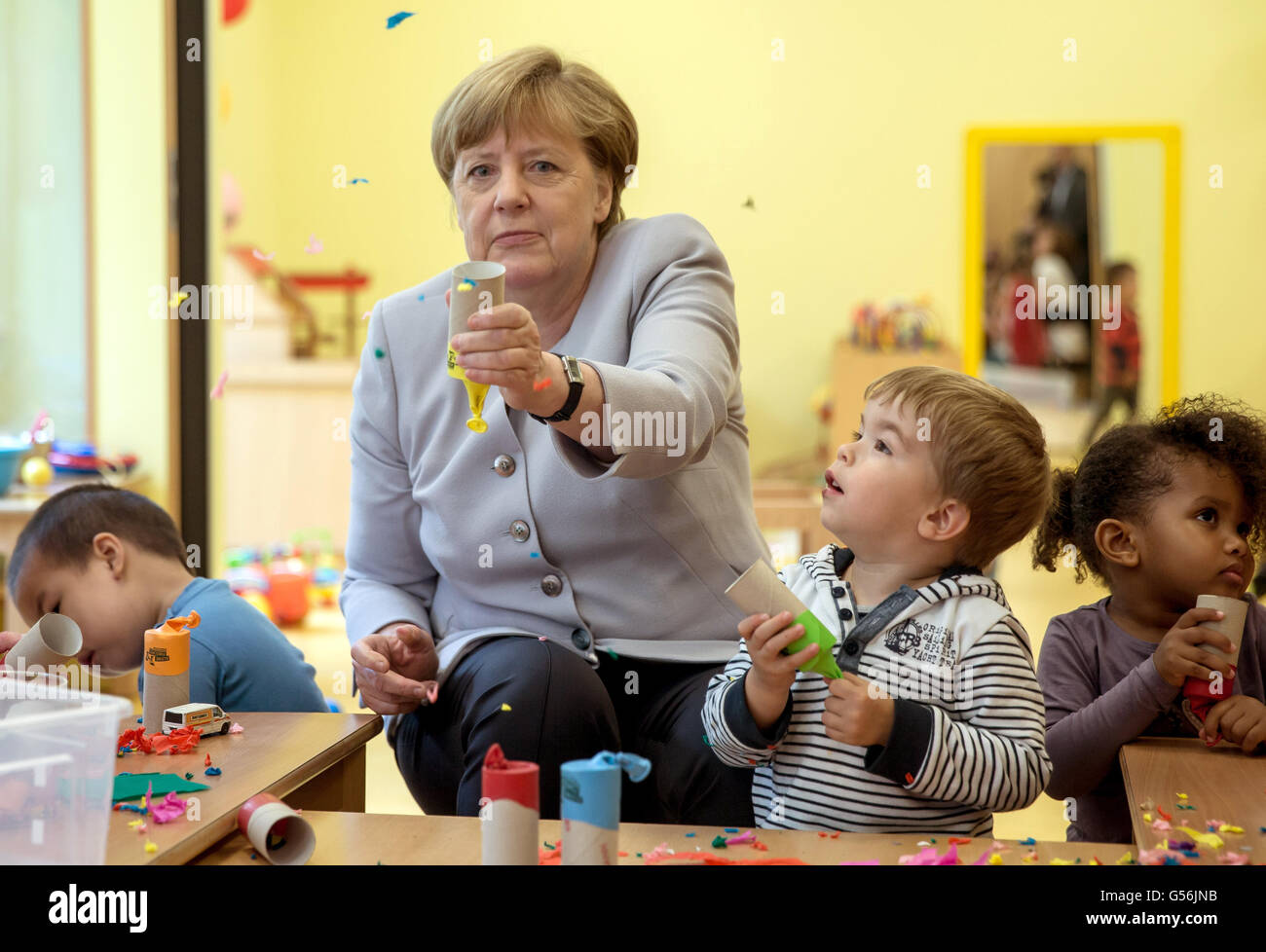 Berlin, Deutschland. 21. Juni 2016. Bundeskanzlerin Angela Merkel sieht wie  ein Papier Feuer Cracker von einer Rolle Toilettenpapier und ein Ballon im  Rahmen einer Kinder Experiment in der Stadt Kita Vorschule in