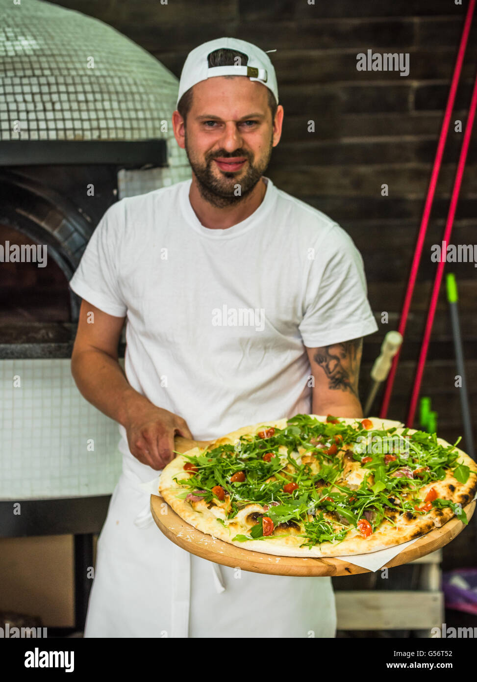 bärtige Jungkoch holding handwerklich traditionellen pizza Stockfoto