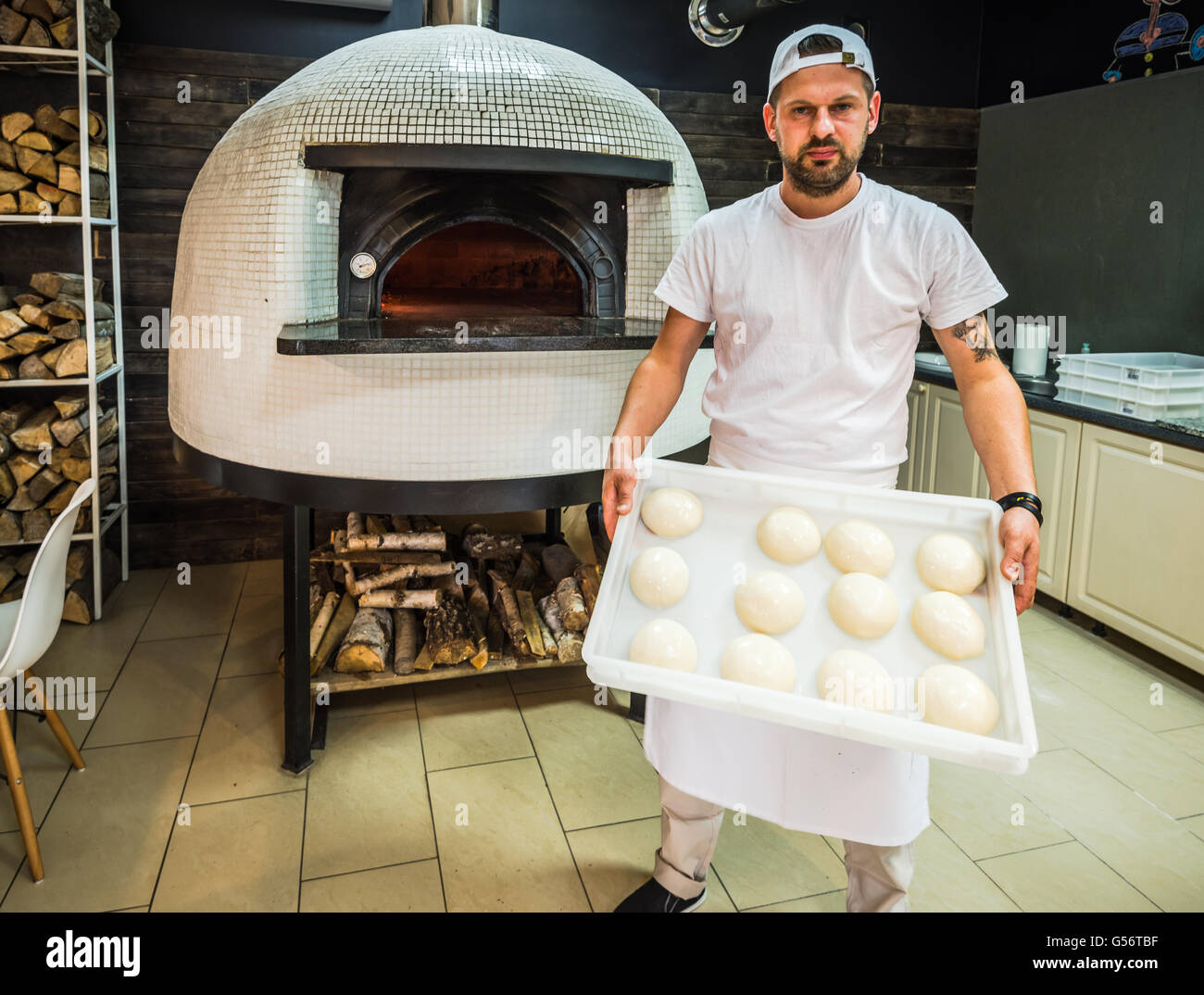 Jungkoch mit Pizzateig in restaurant Stockfoto