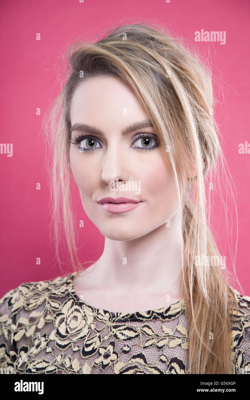 Porträt der jungen Frau mit blonden Haaren auf rosa Hintergrund Stockfoto