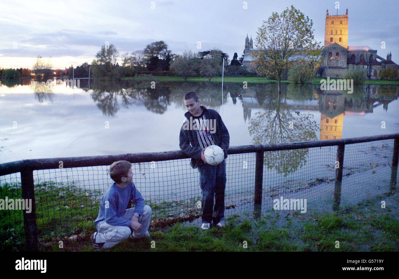 Jack Harries 11 (links) und Thomas Avery 11 kommen optimistisch mit ihrem Ball auf überflutetem Sportplatz an, als die Sonne auf Tewkesbury Abbey untergeht (Hintergrund). Stockfoto