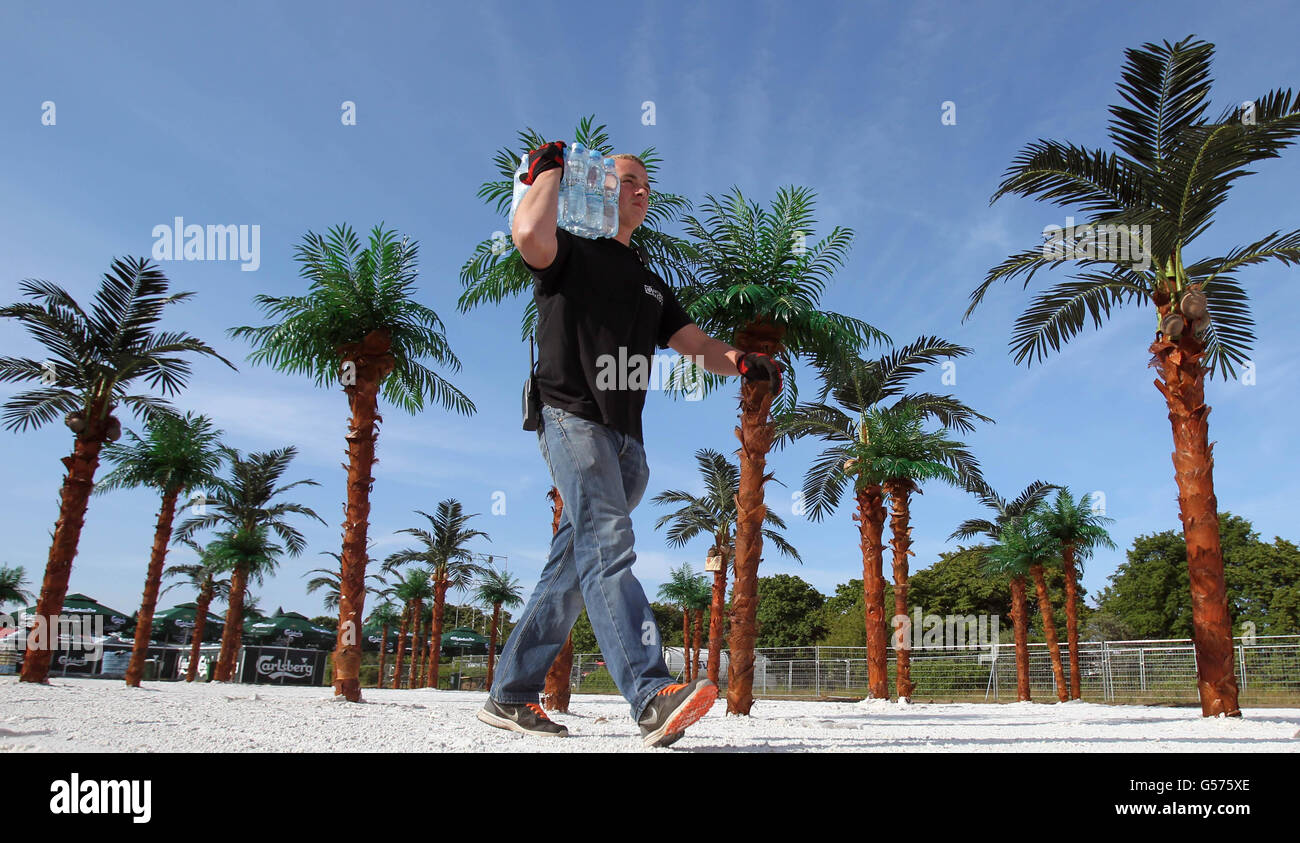 Ein Arbeiter trägt Wasserflaschen über eine gefälschte Wüsteninsel, um sich auf die Tausenden von irischen Fußballfans vorzubereiten, die das Carlsberg Fancamp in der Euro 2012-Basis der Republik Irland in Sopot, Polen, besuchen werden. Stockfoto
