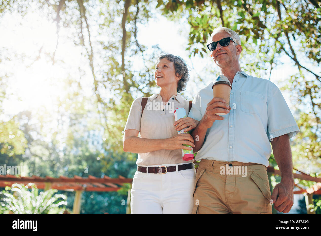 Porträt von senior Touristen zu Fuß durch einen Park. Älteres Paar auf einen Sommerurlaub. Stockfoto