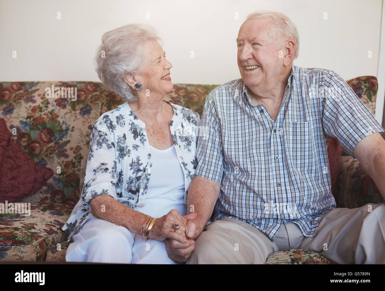 Älteres Paar zusammen Hand in Hand auf dem Sofa sitzen. glücklich, älteres Paar auf der Suche entspannt und zufrieden zusammen. Stockfoto