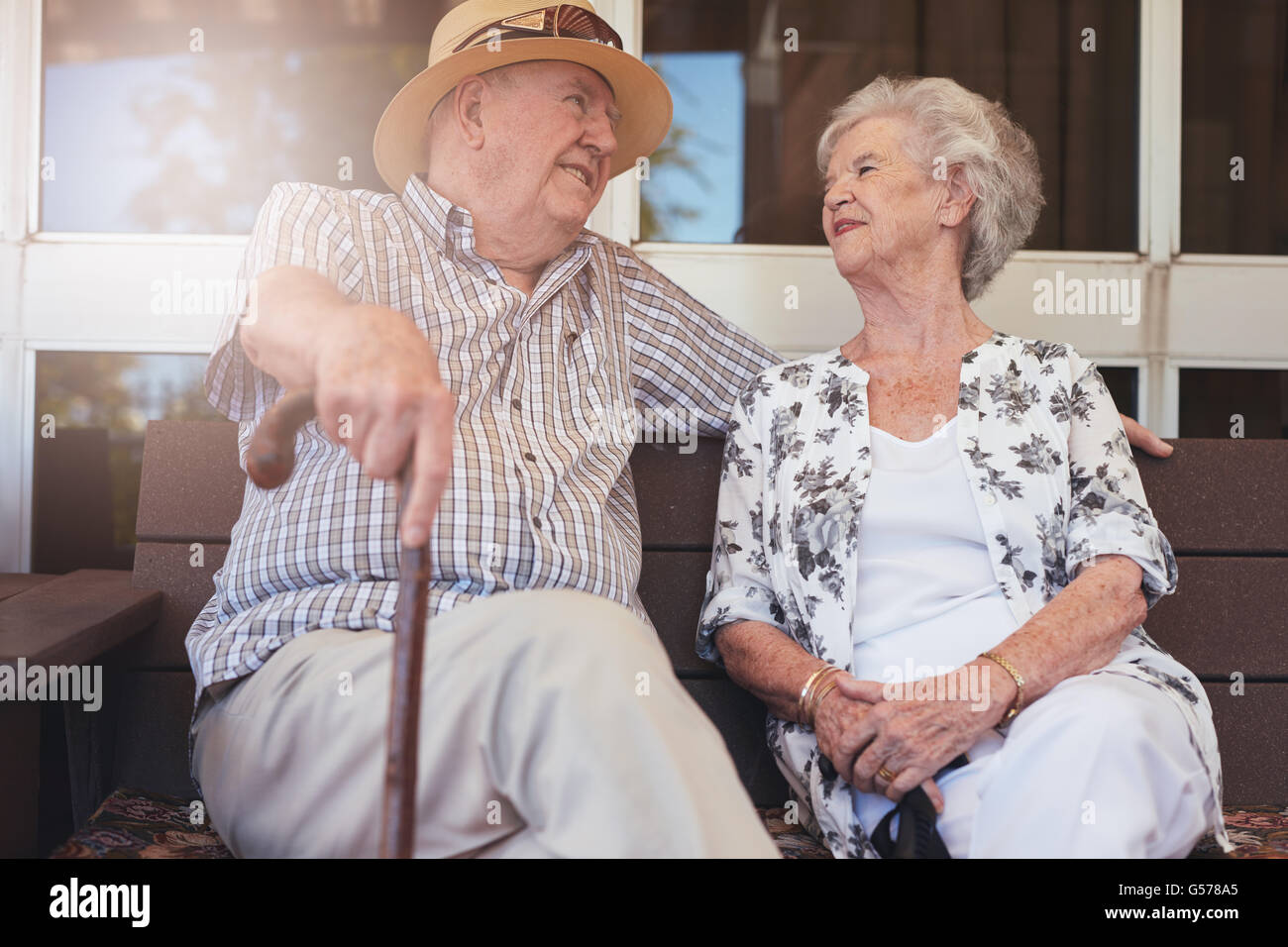 Älteres Paar auf einer Bank außerhalb der eigenen Wohnung zu lieben. Glückliches Ehepaar im Ruhestand eine Pause. Stockfoto