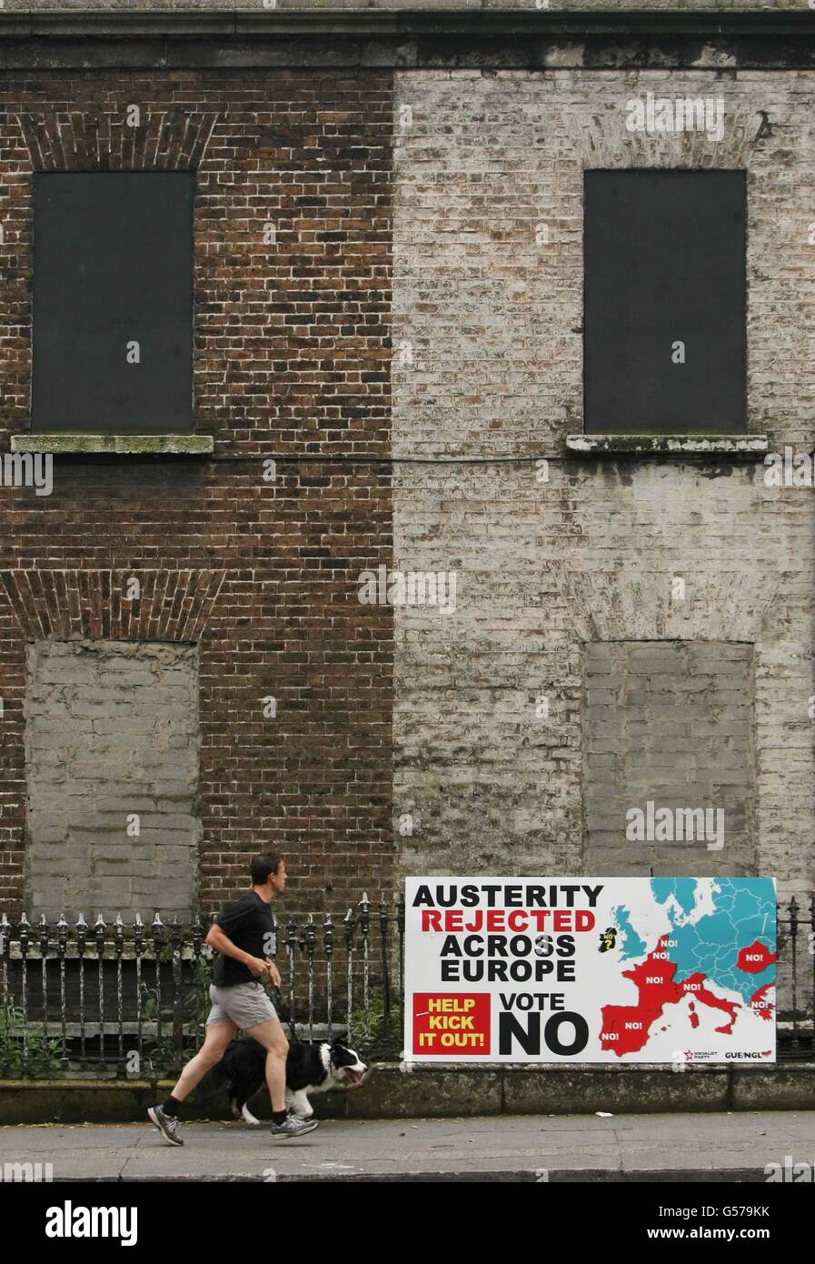 Ein Mann jagt vor dem morgigen Referendum an einem Zeichen gegen den Europäischen Fiskalvertrag in Dublin vorbei. Stockfoto