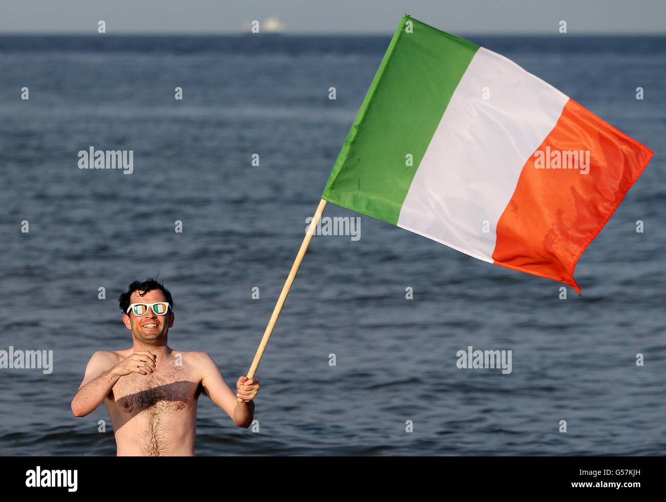 Der Fan der Republik Irland, Emmett Macnamara, steht mit einer irischen Flagge in Sopot, Polen, im Meer. Stockfoto