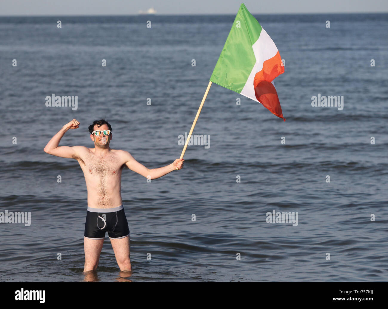 Der Fan der Republik Irland, Emmett Macnamara, steht mit einer irischen Flagge in Sopot, Polen, im Meer. Stockfoto