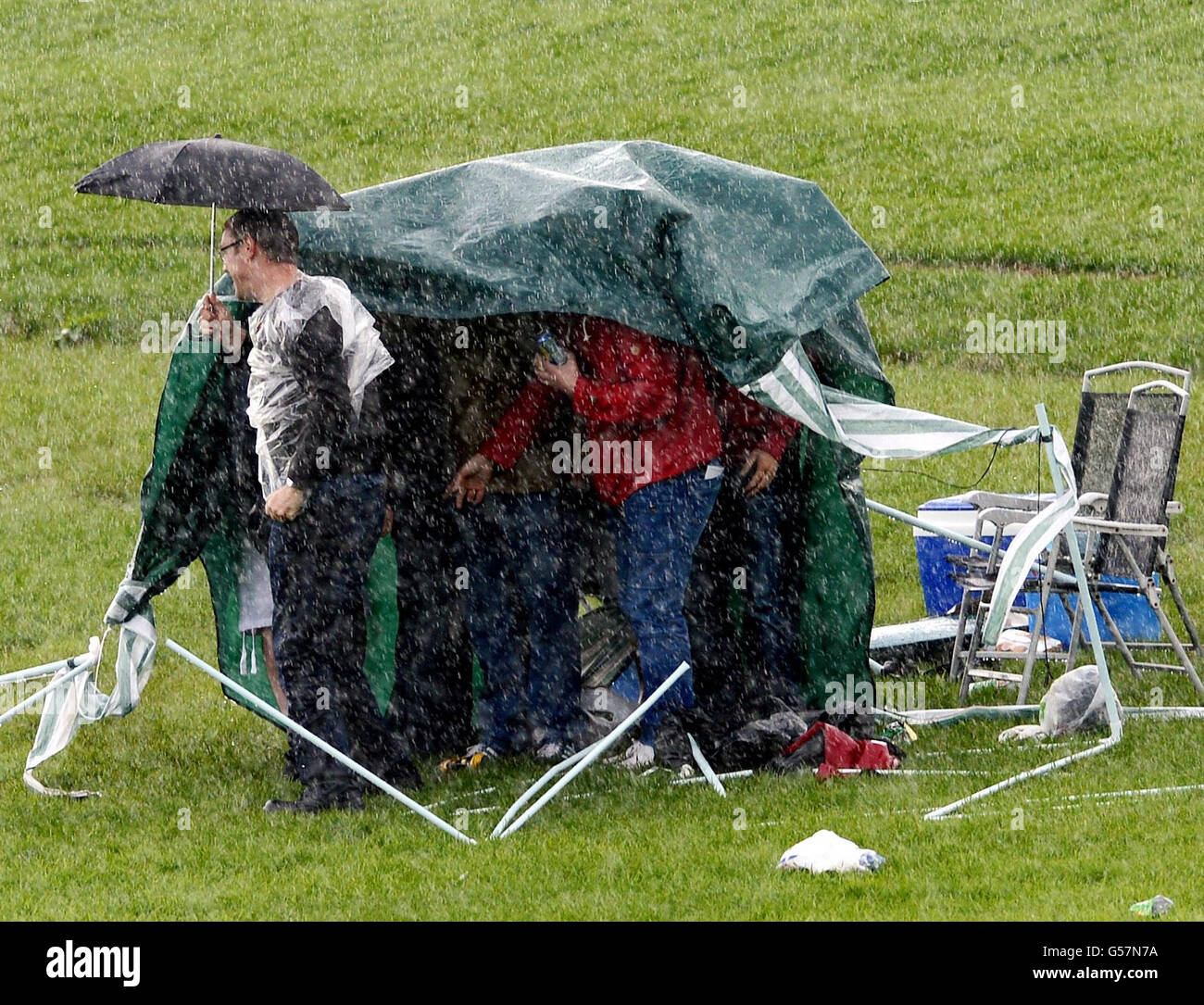 Ein kurzer Regensturm fegt über den Knavesmire, der dieses Zelt wegbläst, während Rennfahrer versuchen, am Mid Summer Raceday während des Juni-Treffens auf der York Racecourse, York, trocken zu bleiben. Stockfoto