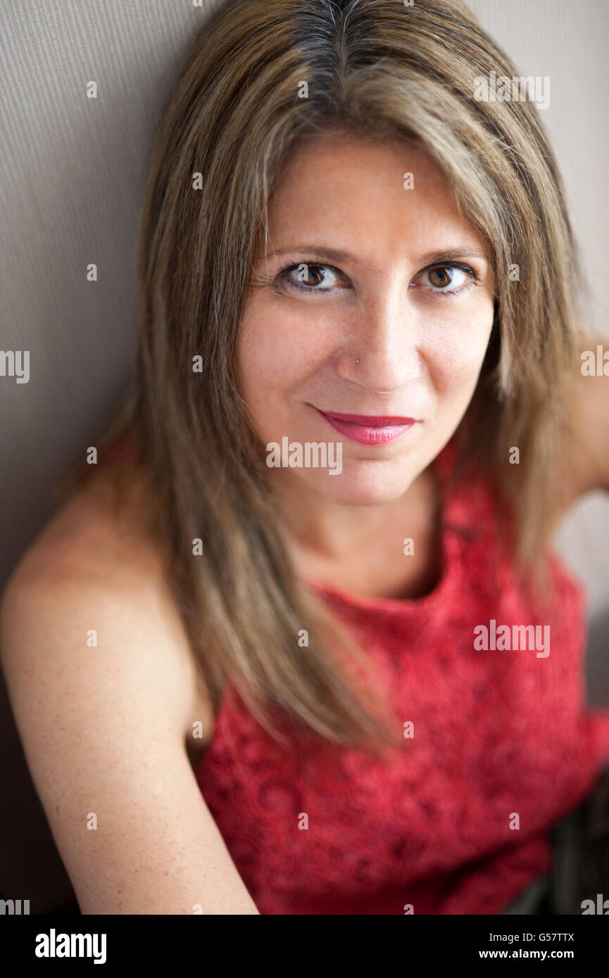 Attraktive Mitte im Alter Frau in die Kamera schaut mit halben Lächeln Gesicht während lehnt sich gegen die Wand hautnah. Stockfoto