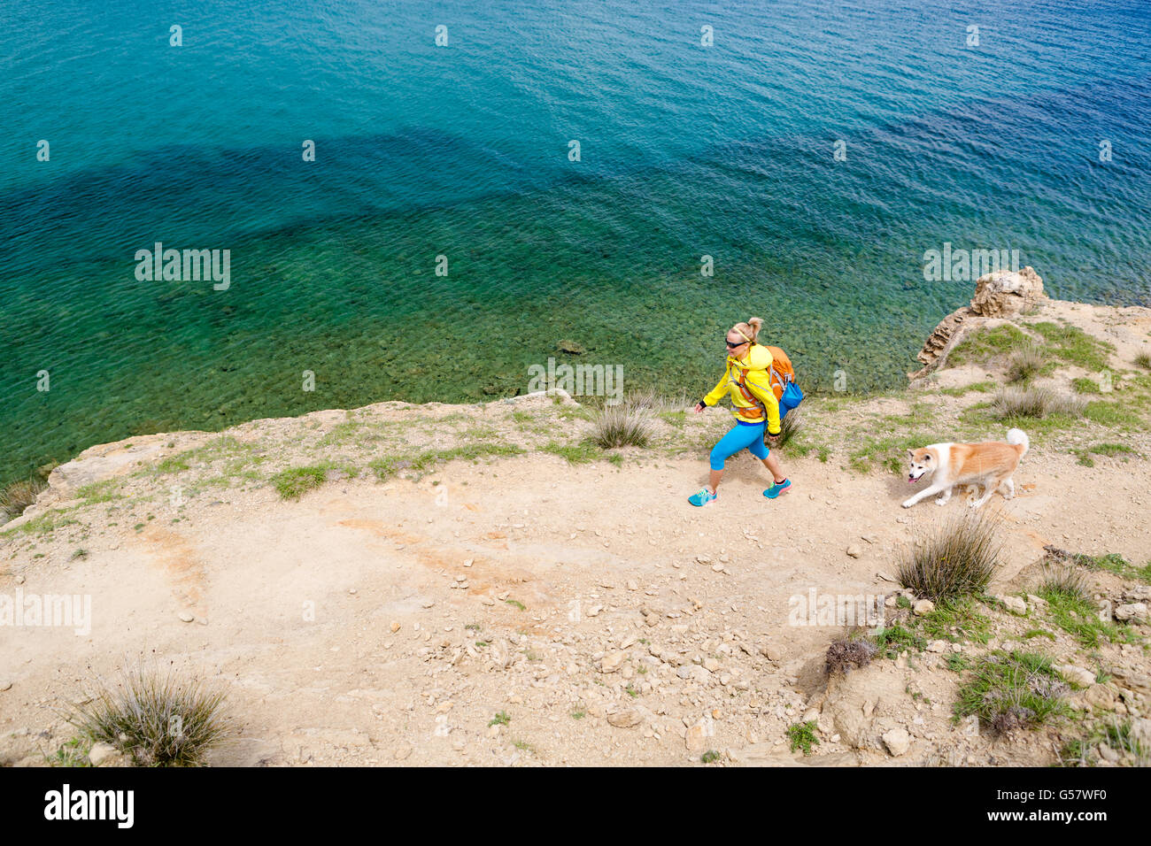 Frau mit Akita Inu Hund am Meer entlang wandern. Erholung und einen gesunden Lebensstil im Freien im Sommerberge und Meer Natur. Stockfoto