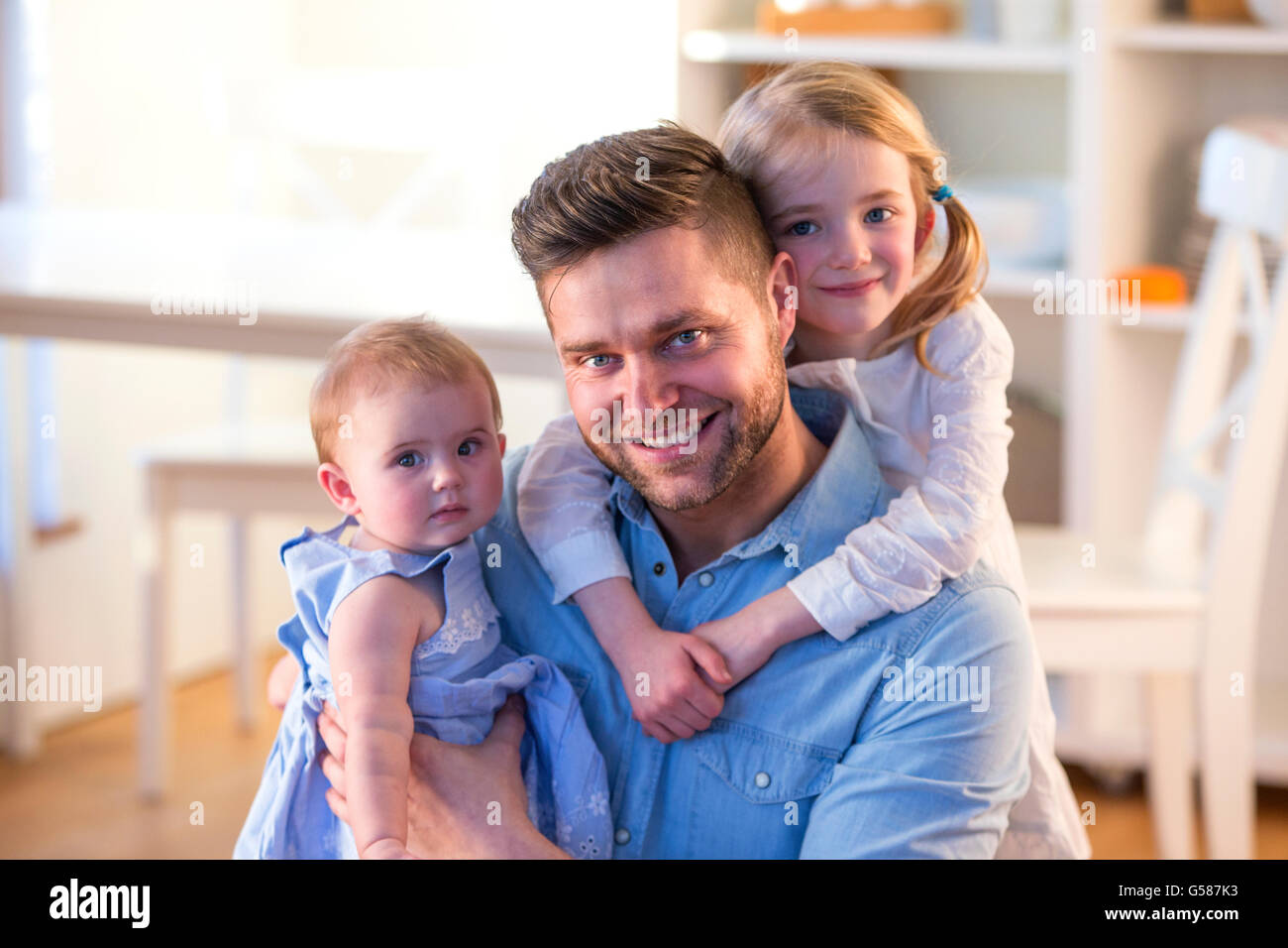Vater mit seinen Töchtern zu Hause für die Kamera Lächeln Stockfoto