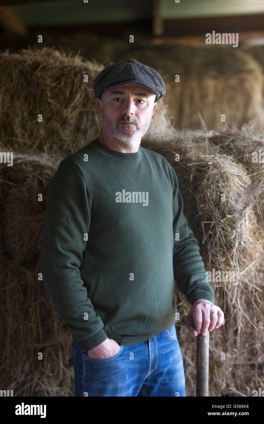 Mann hat eine kurze Pause vom Stall ausmisten. Stockfoto