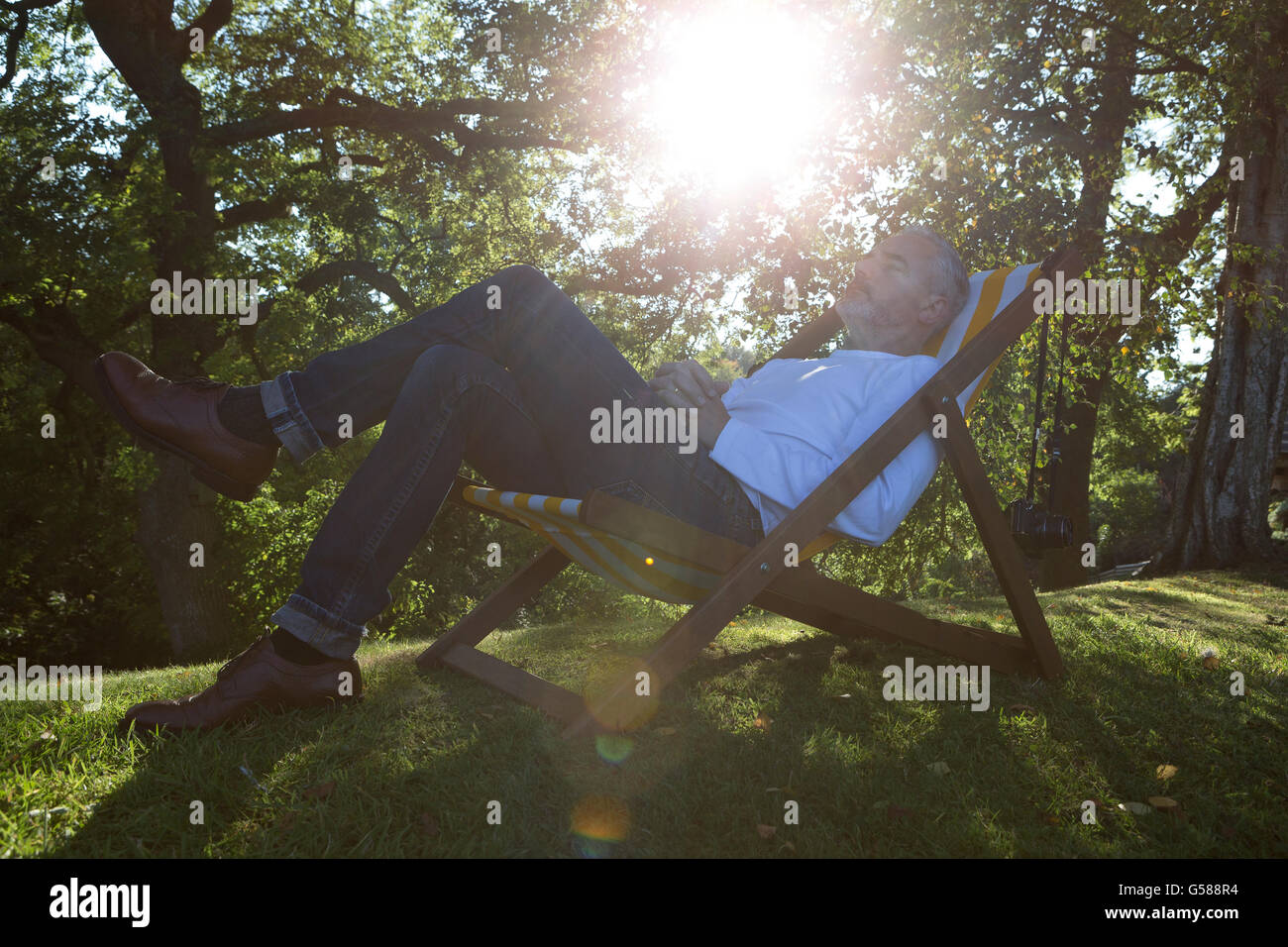 Entspannen Sie sich auf einen Liegestuhl in seinem Garten reifer Mann Stockfoto