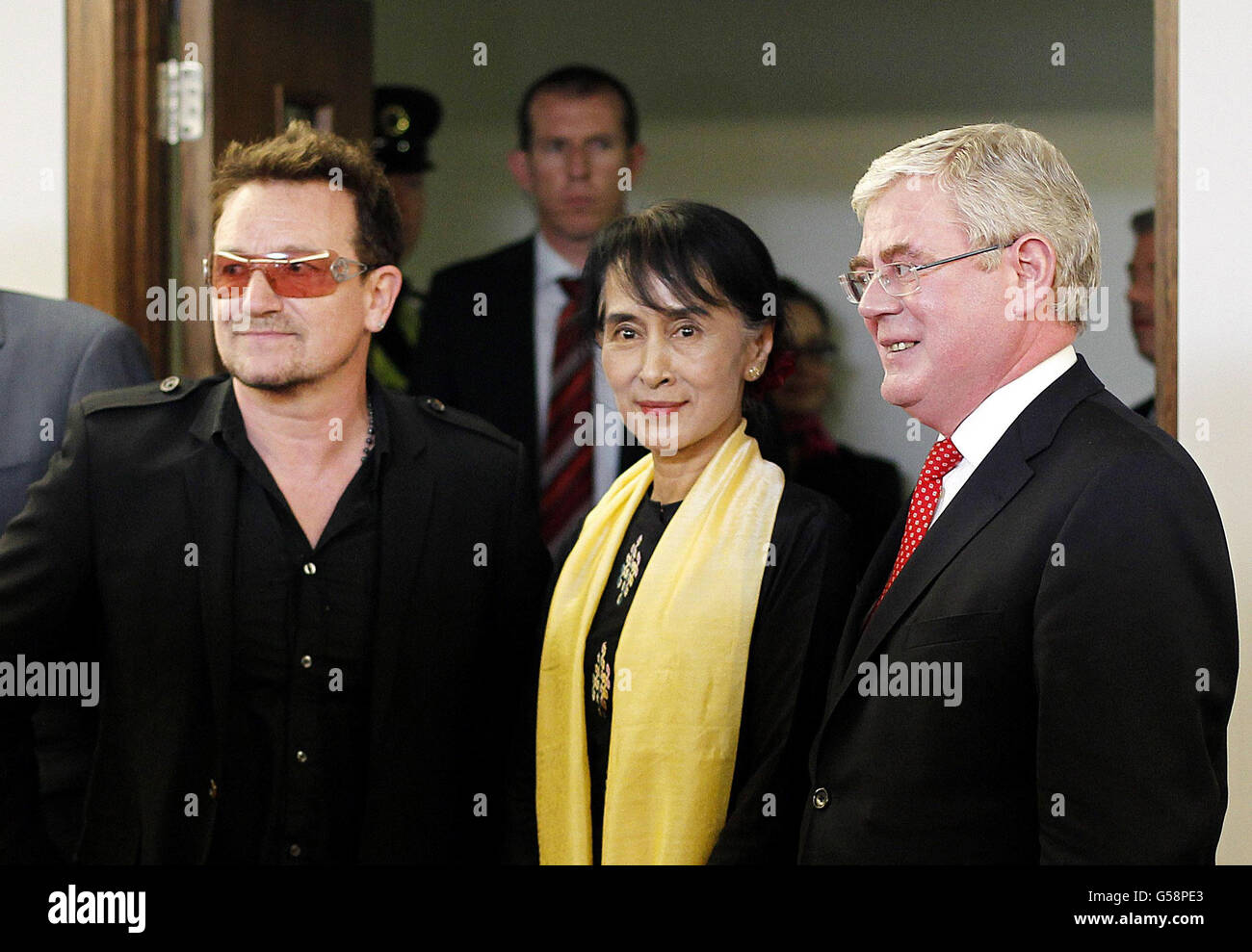 Die birmanische Führerin und Friedensnobelpreisträgerin Aung San Suu Kyi wird von Tanaiste Eamon Gilmore (rechts) und Bono am Flughafen Dublin zu einem sechsstündigen Flugbesuch in die irische Hauptstadt begrüßt. Stockfoto