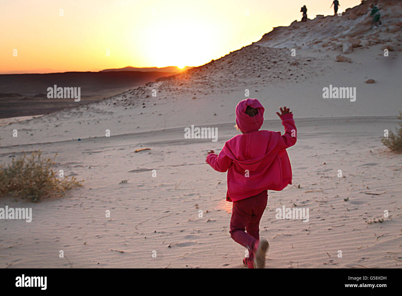 Kleines Mädchen läuft in Richtung auf die untergehende Sonne Stockfoto