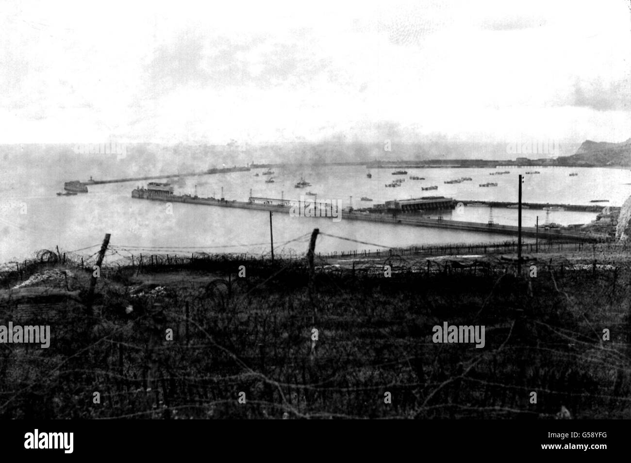1944: Rauch driftet über Dover Harbour, Kent. Im Vordergrund sind Bänder aus Stacheldraht, die als Teil der britischen Küstenverteidigung verwendet werden. Sowohl Marineschiffe als auch zivile Schiffe sind zu sehen. Bild Teil der PA Zweiten Weltkrieg Sammlung. Stockfoto