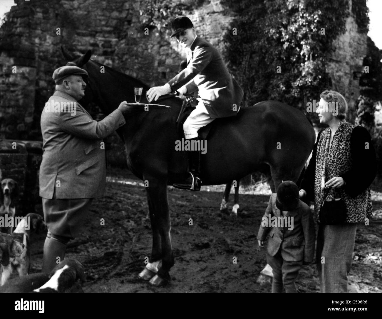 FUCHSJAGD 1947: Beim Treffen der East Sussex Foxhounds auf der Court Lodge Farm, Crowhurst, Sussex, nimmt Lord Burghley einen Steigbügelbecher von Herrn T.W.Croft (dem Besitzer), beobachtet von Lady Burghley und der kleinen Ann Croft. Stockfoto