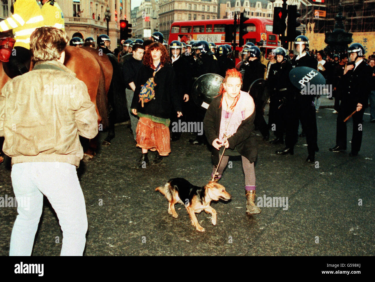 Eine Frau führt ihren Hund von einer Reihe von Polizisten in Bereitschaftskleidung weg, nachdem ein Protest gegen die sogenannte Poll Tax ausgebrochen war, der zu einem Aufruhr auf den Trafalgar Square und die Umgebung von Central London führte. Stockfoto