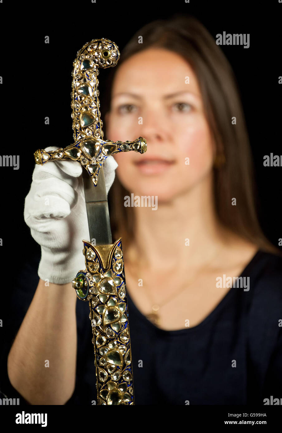 Die Kuratorin der Ausstellung, Caroline de Guitaut, hält ein Schwert und eine Scheide von Jaipur, besetzt mit 719 Diamanten mit einem Gewicht von insgesamt 2,000 Karat, die König Edward VII. Ursprünglich für seine Krönung im Jahr 1902 vom Maharadscha von Jaipur, Teil der „Diamanten: Eine Jubiläumsausstellung im Buckingham Palace im Zentrum von London vom 30. Juni bis 8. Juli 2012 und vom 31. Juli bis 7. Oktober 2012. Stockfoto Die Kuratorin der Ausstellung, Caroline de Guitaut, hält ein Schwert und eine Scheide von Jaipur, besetzt mit 719 Diamanten mit einem Gewicht von insgesamt 2,000 Karat, die König Edward VII. Ursprünglich für seine Krönung im Jahr 1902 vom Maharadscha von Jaipur, Teil der „Diamanten: Eine Jubiläumsausstellung im Buckingham Palace im Zentrum von London vom 30. Juni bis 8. Juli 2012 und vom 31. Juli bis 7. Oktober 2012. Stockfoto