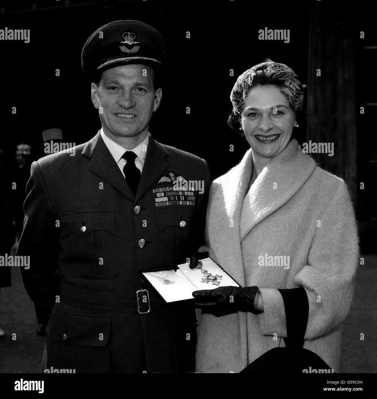 1960: Gruppenkapitän James 'Johnnie' Johnson, das Kämpferass des Zweiten Weltkriegs, mit seiner Frau Paula vor dem Buckingham Palace, London, Nachdem er zum Kommandanten der Militärdivision des Order of the British Empire ernannt wurde. Die Königin Mutter hielt die Investitur im Namen der Königin. Stockfoto