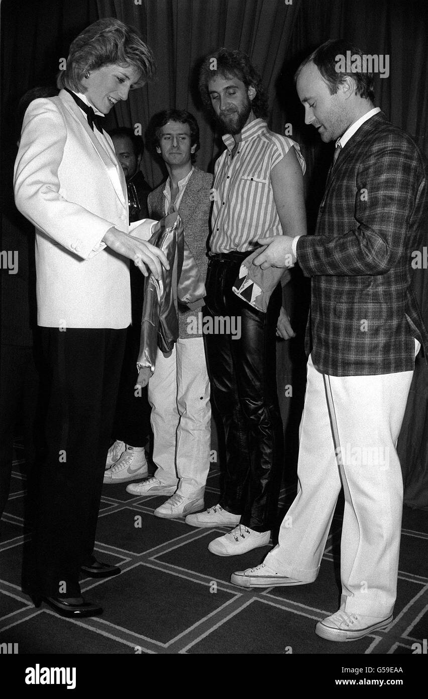 Die Prinzessin von Wales nimmt eine Jacke mit einer gestickten Goldkrone für Prinz William vom Sänger Phil Collins (R) der Popgruppe Genesis an, bevor die Band ein Royal Charity-Konzert im National Exhibition Centre in Birmingham gab. Stockfoto