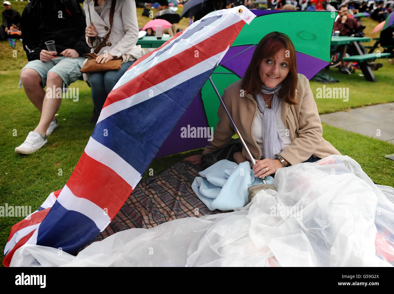 Tennisspieler schützen sich am siebten Tag der Wimbledon Championships 2012 im All England Lawn Tennis Club in Wimbledon vor dem Regen auf Murray Mount. Stockfoto