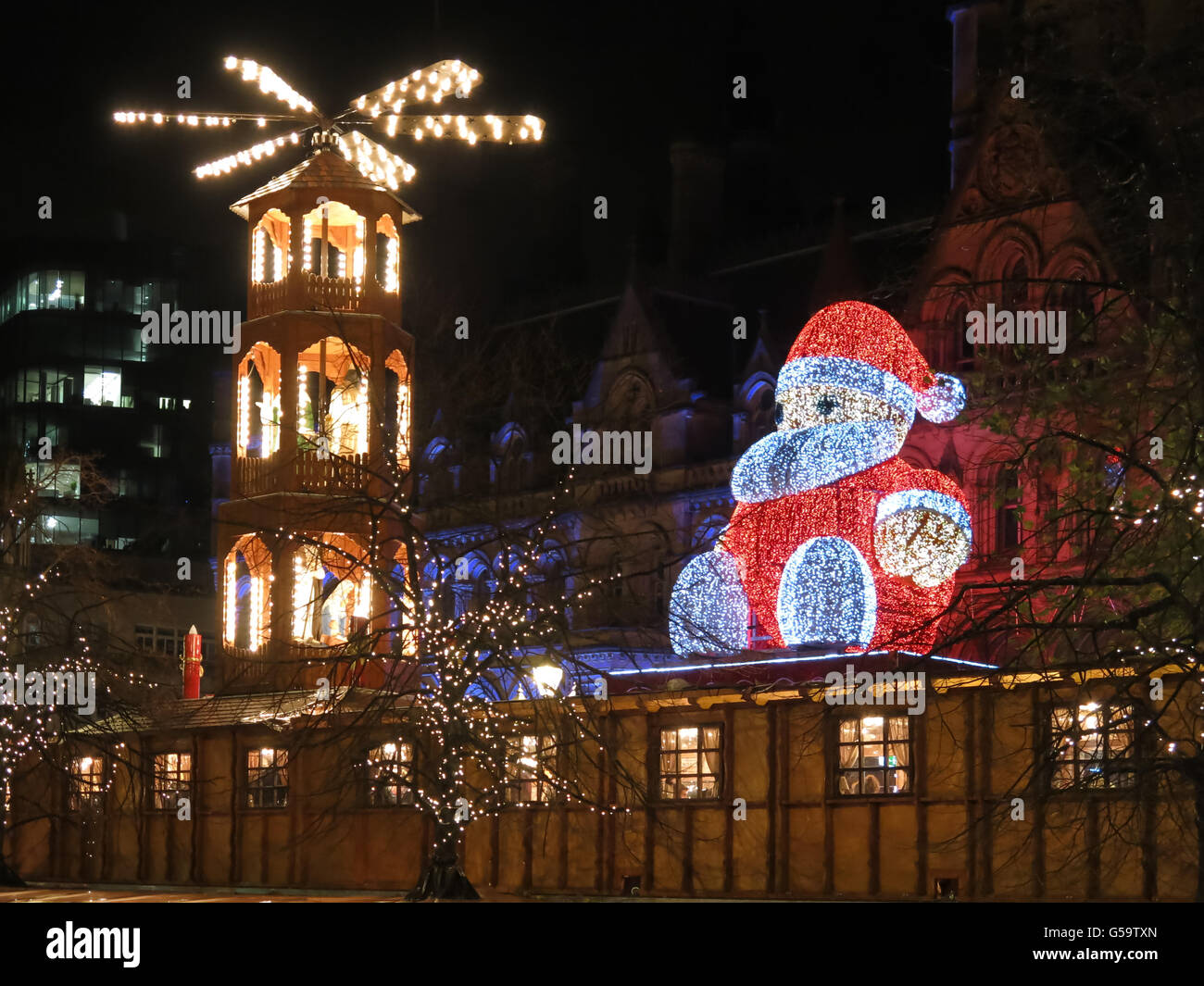 Weihnachtsmarkt und Big Santa Claus sitzen auf Rathaus am Albert Square bei Nacht, Manchester, England, Vereinigtes Königreich Stockfoto