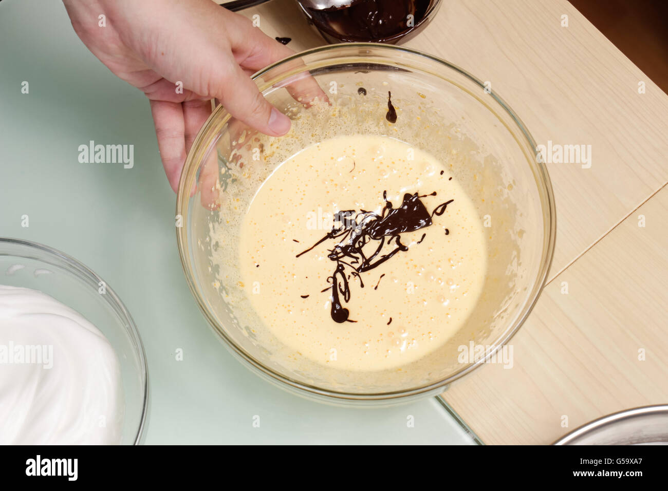 Schüssel geschlagenes Ei York Hand mit Schokolade geschmolzen Stockfoto