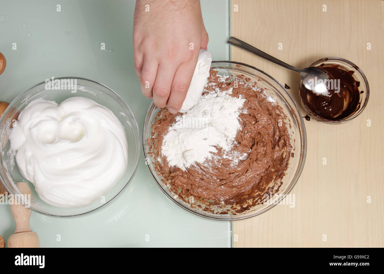 Closeup Hand hinzufügen Eiweiß Mehl Schlagsahne Schokolade. Kochen Kuchen Schokolade Stockfoto