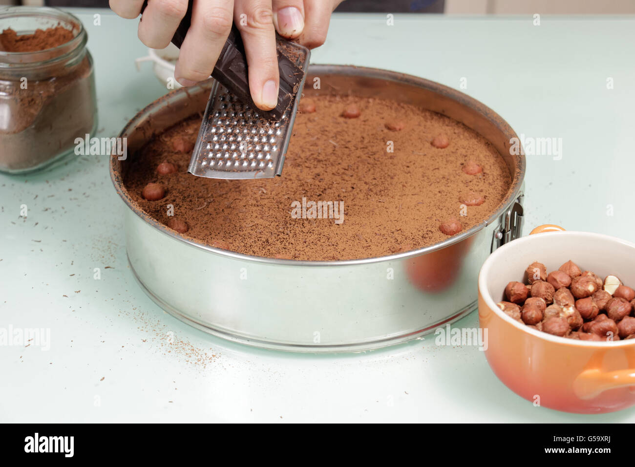 Hand Reiben Schokolade auf Schokoladenkuchen Sacher Sachertorte. Stockfoto