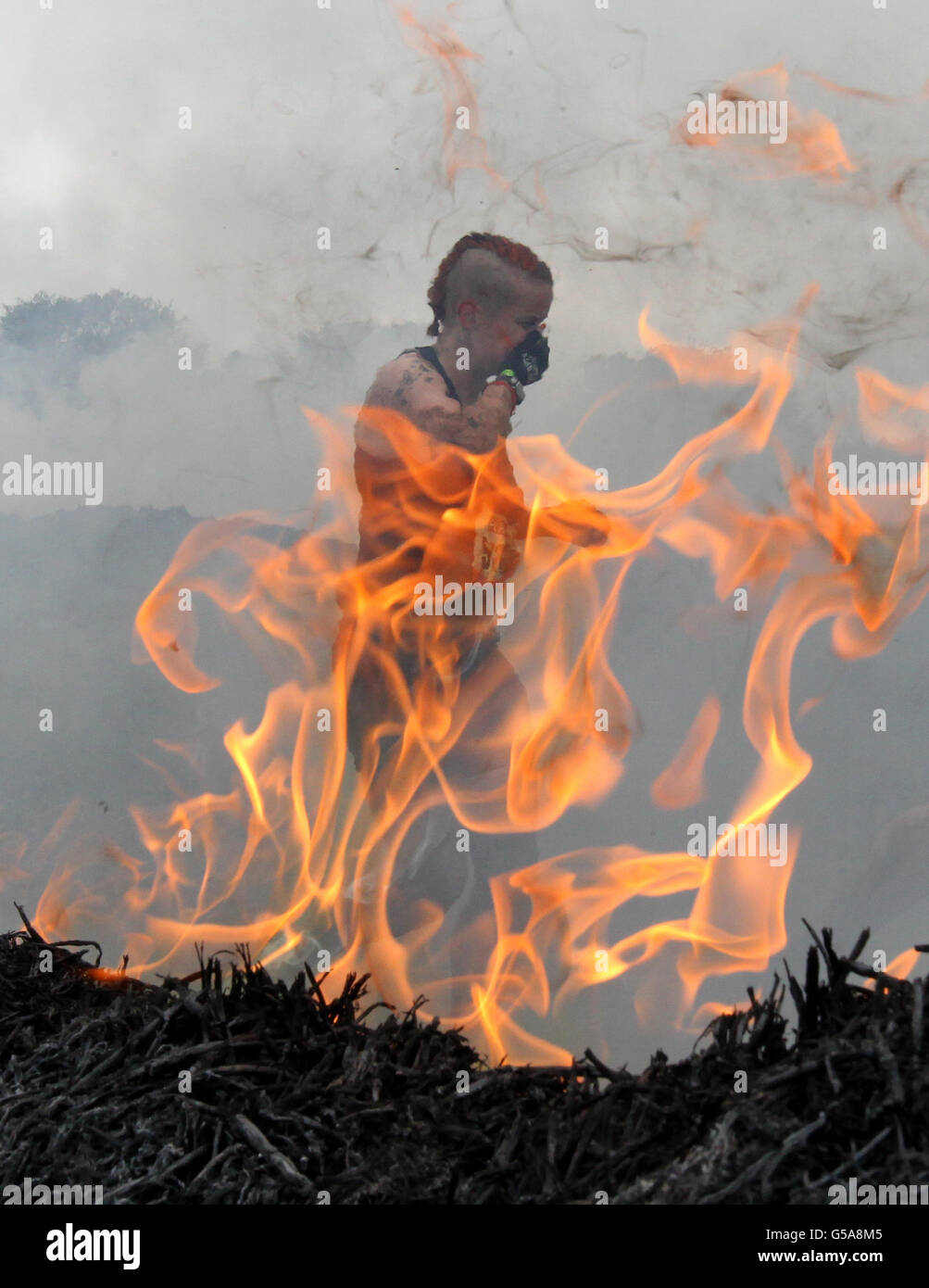 Ein Teilnehmer bewältigt das Firewalker-Hindernis während der 2012 Tough Mudder Extreme Endurance Challenge, die auf dem Gelände von Drumlanrig Castle and Country Estate in Dumfriesshire stattfand. DRÜCKEN Sie VERBANDSFOTO. Bilddatum: Samstag, 14. Juli 2012. Der 12 Meilen lange Hindernisparcours wurde von Special Forces entworfen, um Fitness, Ausdauer und mentale Stärke zu testen. Über 5,000 Teilnehmer nehmen das ganze Wochenende mit 100,000 Gallonen Schlamm, die Teilnehmer trotzten hüfthohen Sümpfen, unterirdischen Tunneln, Fire Walking und Elektroschocks unter den 22 Hindernissen. Bildnachweis sollte lauten: Andrew Stockfoto