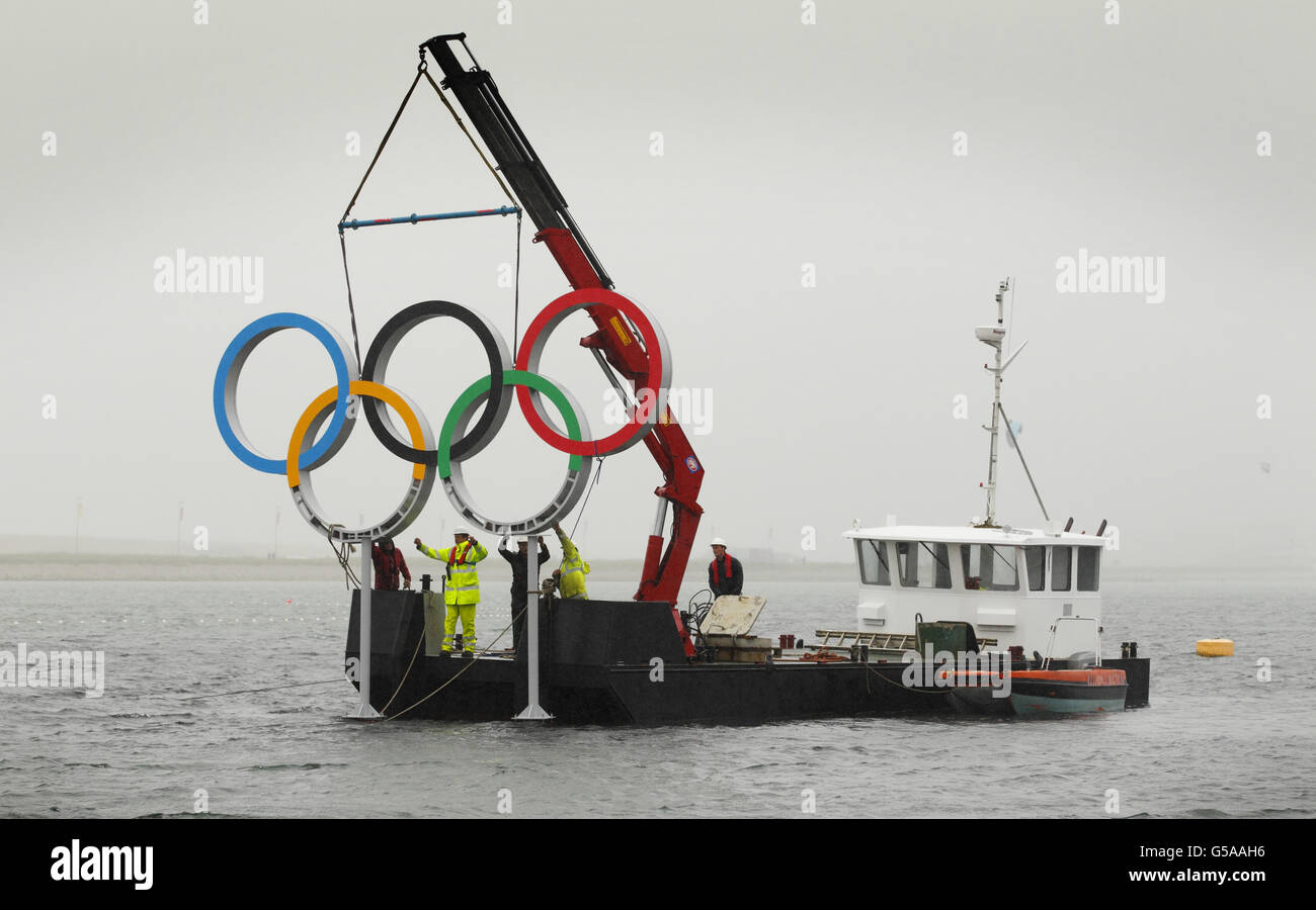 Ingenieure installieren einen Satz olympischer Ringe im Meer an der Weymouth und Portland Sailing Academy, Weymouth. Stockfoto