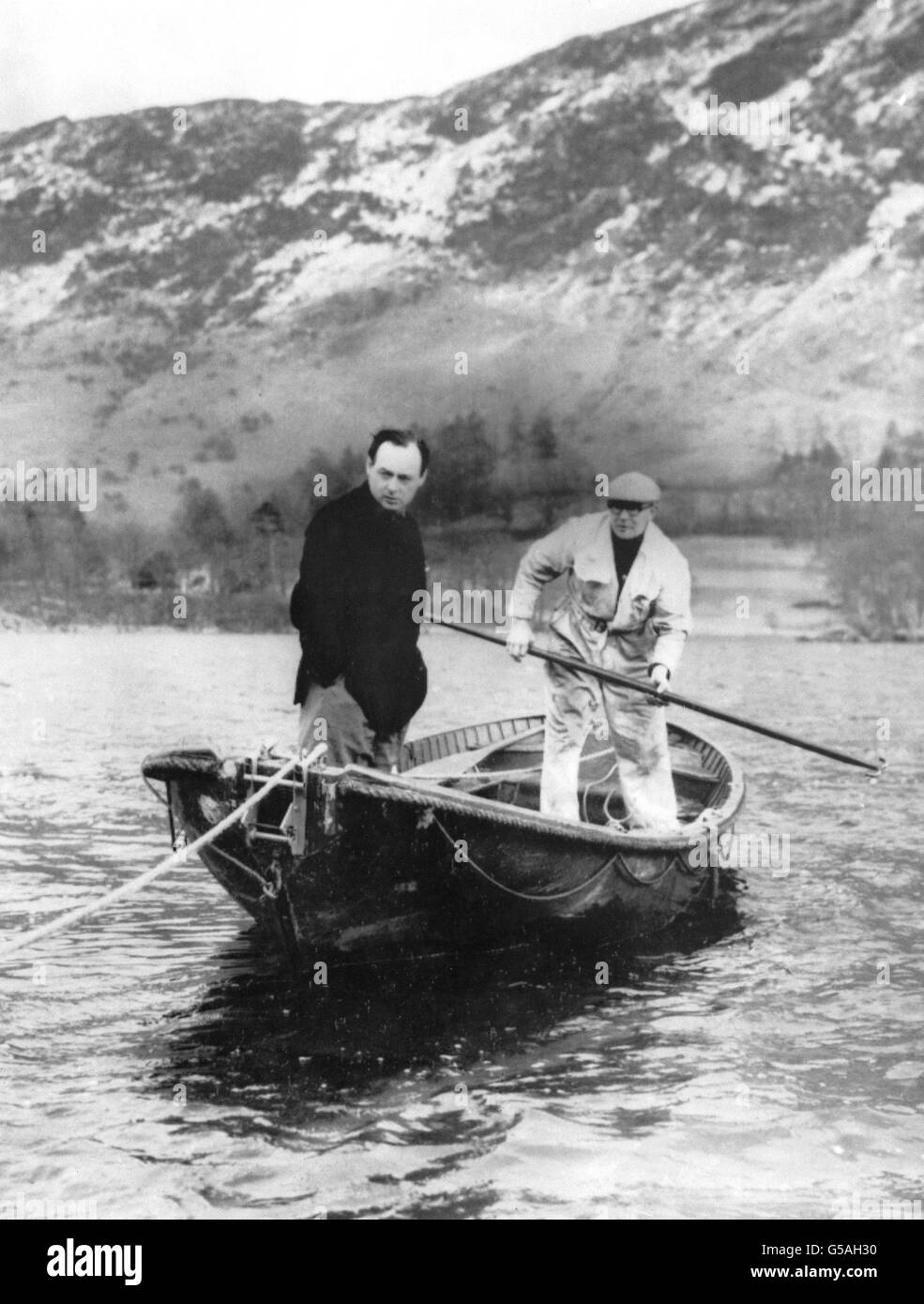 Donald Campbell (l.) und sein Chefmechaniker Leo Villa (r.) gehen wegen eines Last-Minute-Anfahrens zum Ruderboot und nicht zu seinem Hochgeschwindigkeitsboot "Bluebird", um das Gleisgebiet von Ullswater, Cumberland, zu inspizieren. Stockfoto