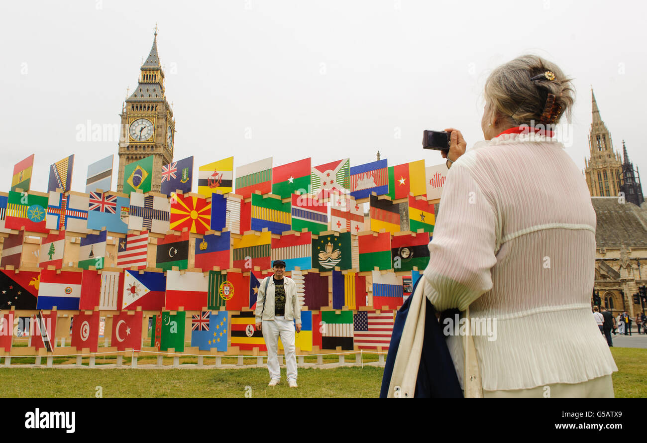 Touristen posieren für Fotos neben einem Kunstwerk von Nationalflaggen der konkurrierenden olympischen Nationen auf dem Parliament Square im Zentrum Londons. Stockfoto