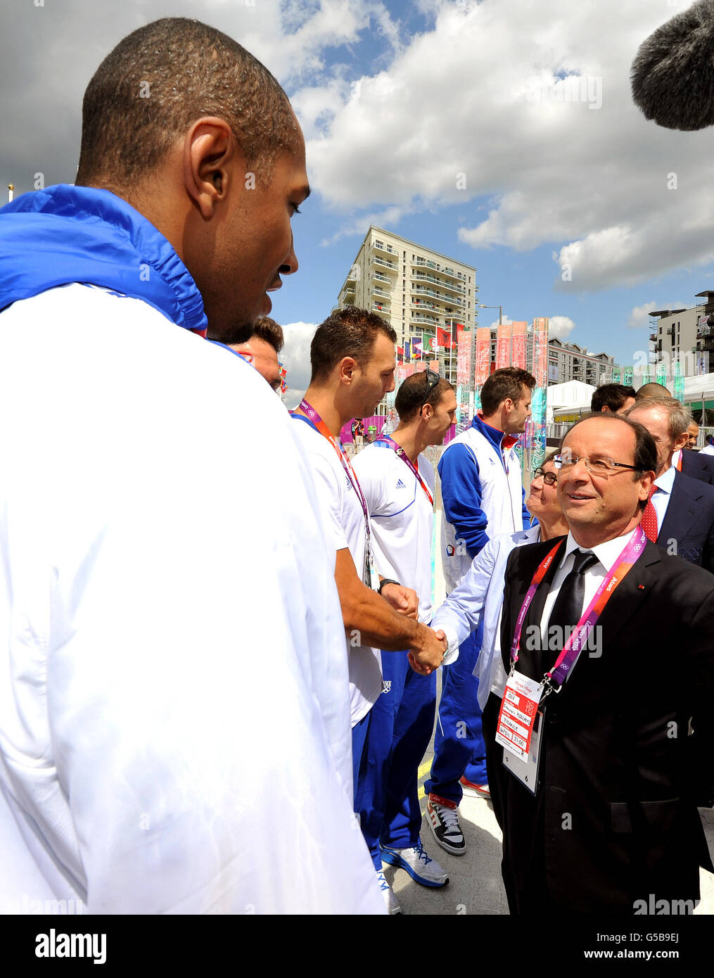 Der französische Präsident Francois Hollande spricht mit einem Mitglied der französischen Basketballmannschaft (Name nicht angegeben) während der Reise des Präsidenten in das Dorf der Olympischen Athleten in Stratford, Ost-London. Stockfoto